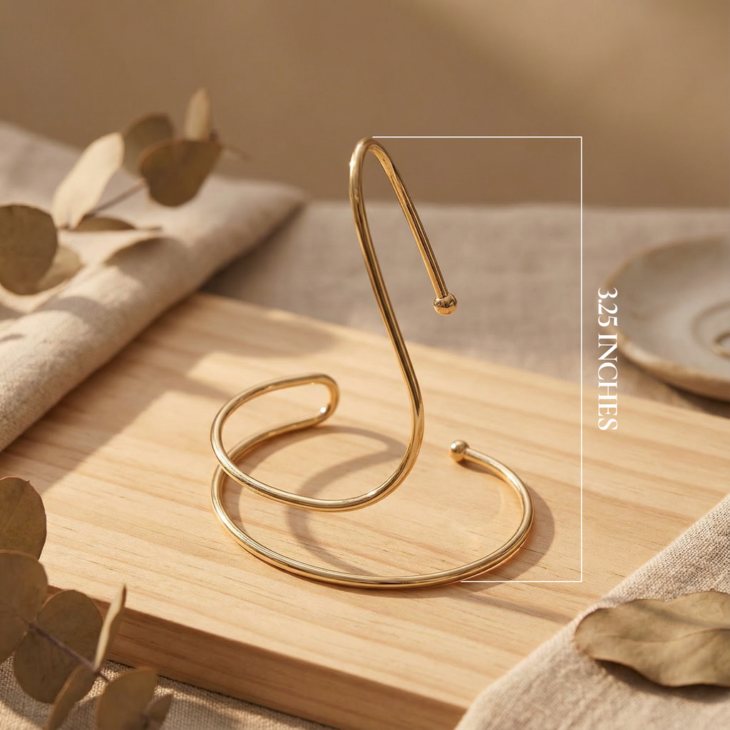 Gold metal stand on a wooden surface with leaves and fabric in the background