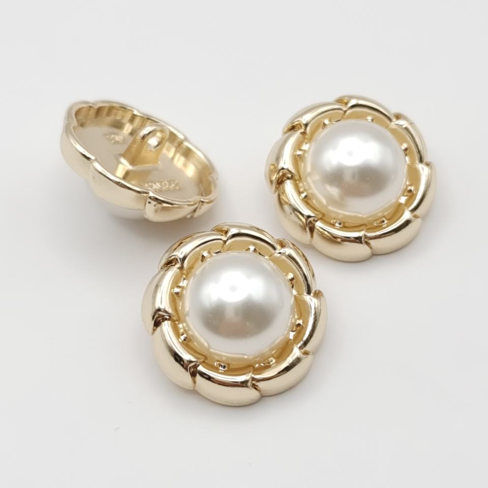 Pair of gold button  pearl centers on a light gray background