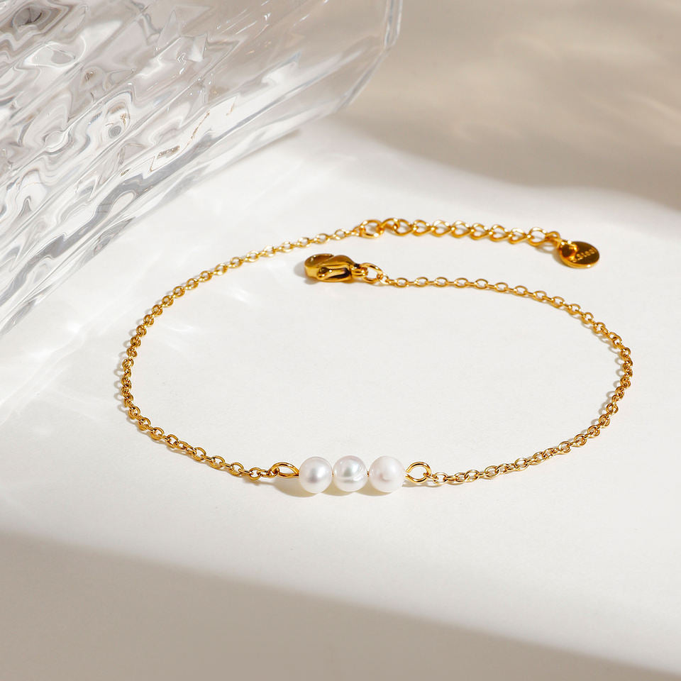 Gold anklet with pearls on a white surface