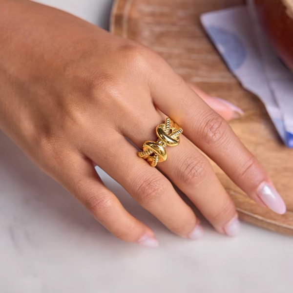 Hand wearing a gold ring on a light background